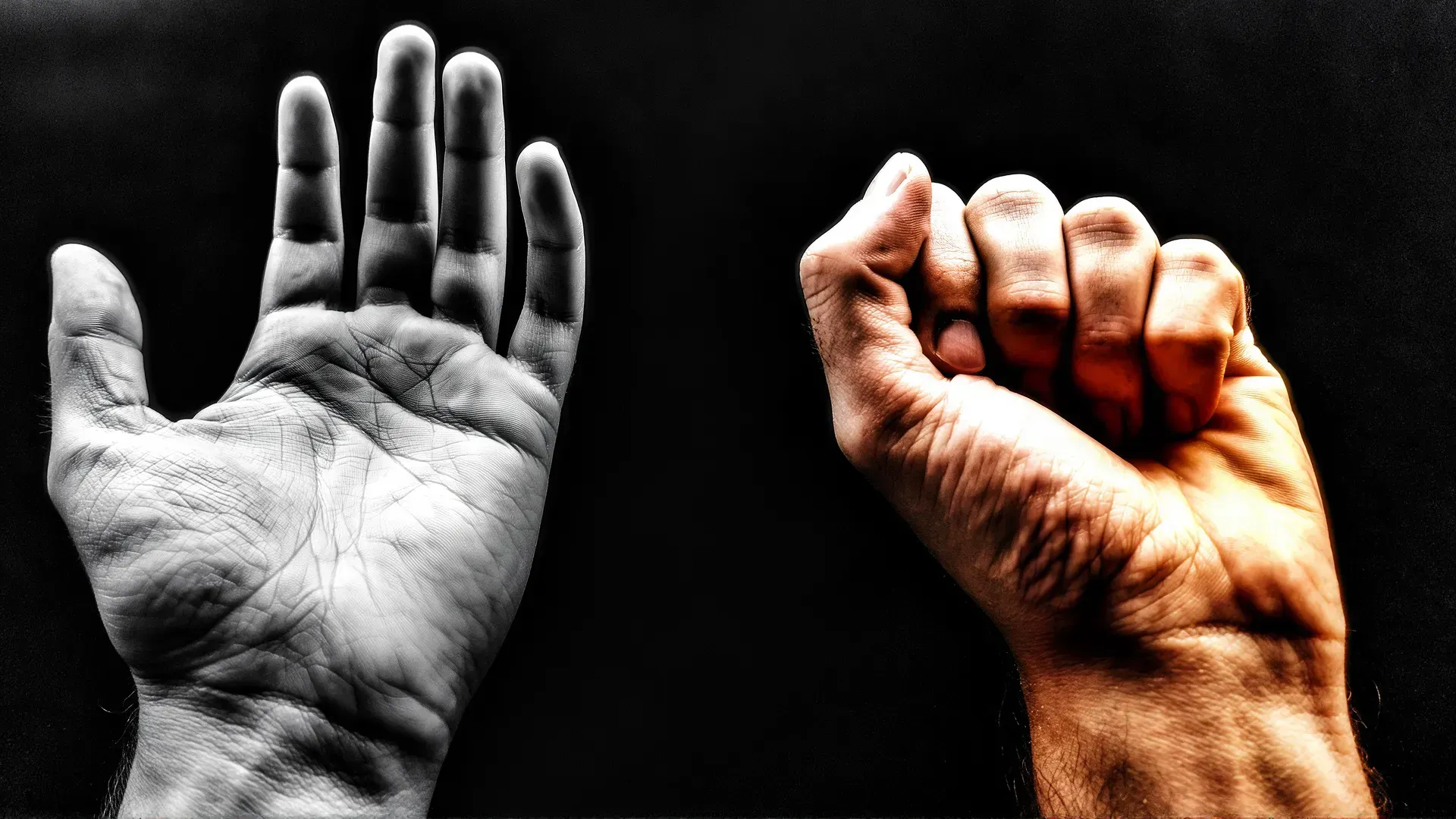 Two human hands on a dark background — one open and relaxed, fingers spread; the other closing into a clenched fist, lit in warm amber light.