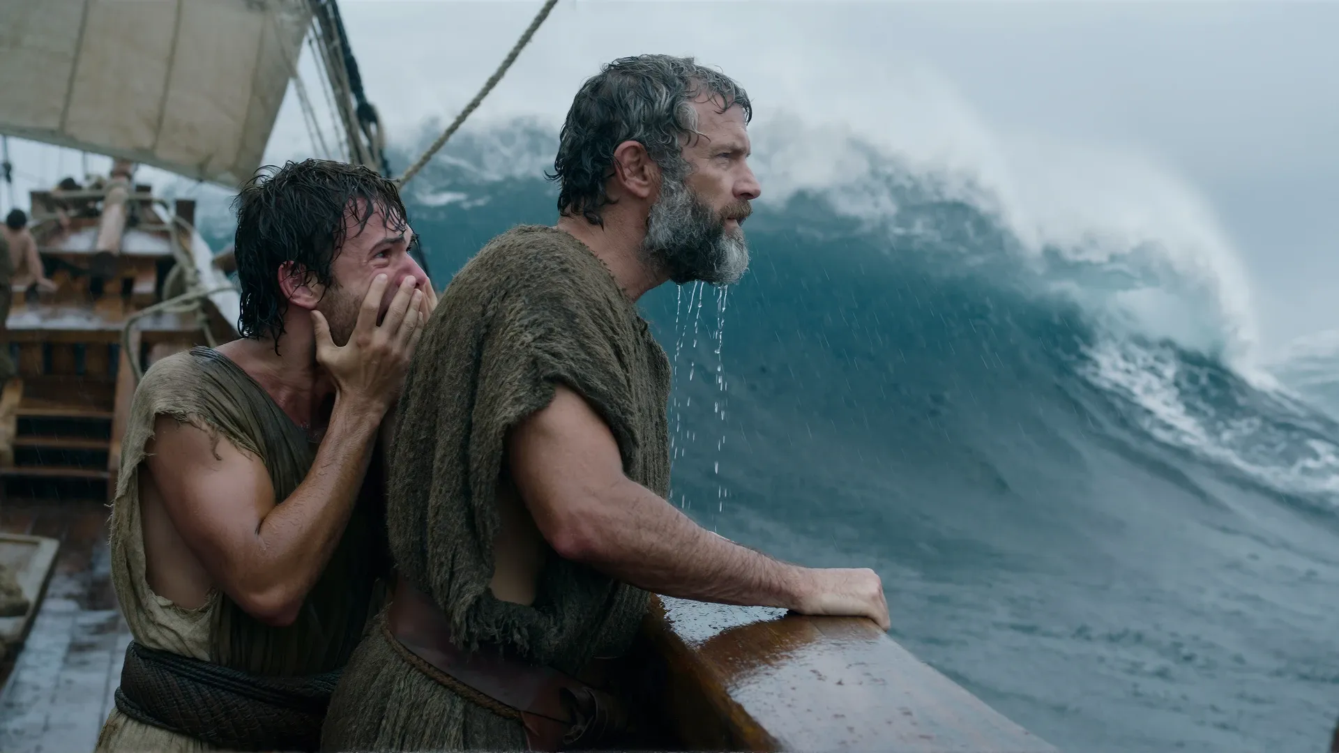 Two men at the rail of an ancient Greek ship in a storm: an older bearded man stands composed, watching a towering wave, while a younger man beside him recoils in terror.